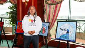 Ojibway artist Jay Bell Redbird with several of his original paintings at the Friends United Halifax Exhibition 2013 at Casino Nova Scotia in Halifax, Nova Scotia.