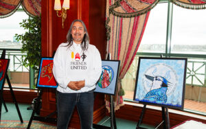 Ojibway artist Jay Bell Redbird with several of his original paintings at the Friends United Halifax Exhibition 2013 at Casino Nova Scotia in Halifax, Nova Scotia.