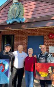 Friends United representatives and RCMP officer with Indigenous artwork at the New Glasgow RCMP detachment